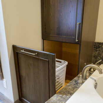 A clothes hamper can be hidden in a cabinet with a vanity pull-out cabinet from Dura Supreme.
